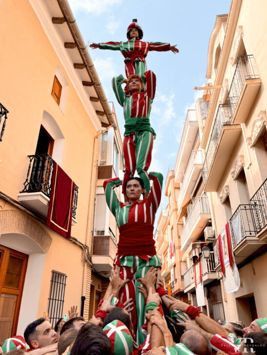 People dressed in red and green build a four level high human tower