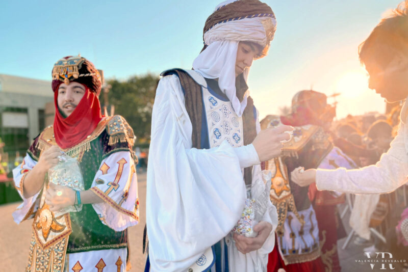A young man in Arabic clothes hands candy to the children at the Cavalcade of the Magi