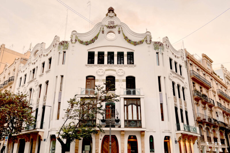 An Art Nouveau-inspired white building adorned with organic-shaped windows and floral elements