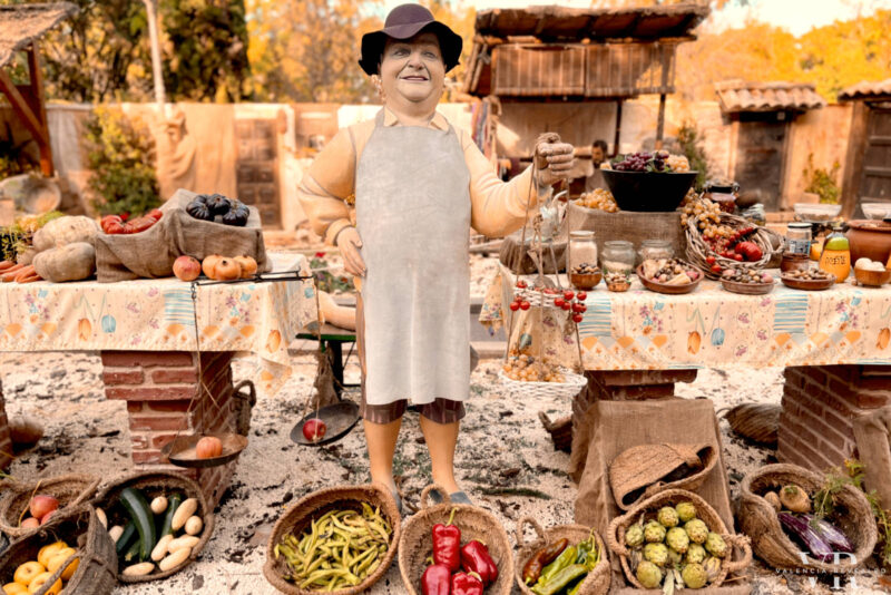 A life-size figure of a market vendor surrounded by fruits an vegetables in Xàtiva