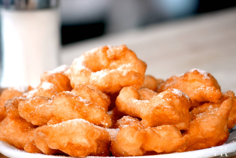 Buñuelos sprinkled with sugar on a white plate