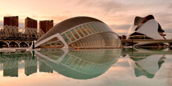 Futuristic buildings of the City of Arts and Sciences reflected in tranquil pools of water at sunset