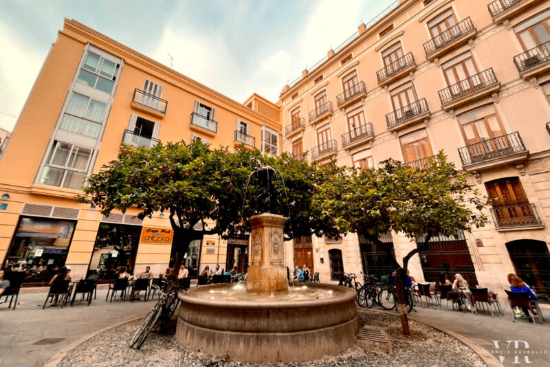 Plaza del Negrito in Valencia with water fountain in the middle and people sitting on a terrace