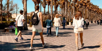 Young people walking on Valencia' palm tree lined promenade in May