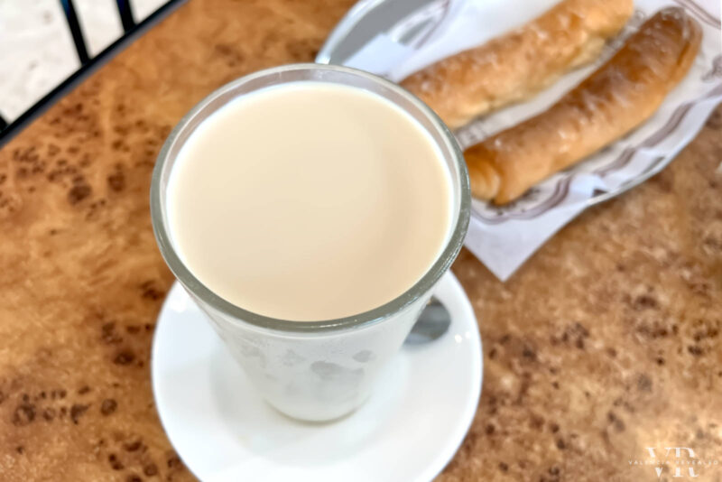 A glass of horchata and a plate with fartons on a table