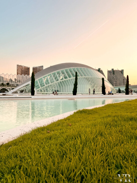 A futuristic looking building surrounded by pools of water and lush green grass