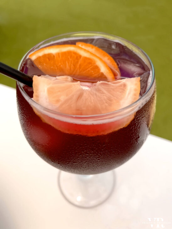 A large glass of wine cocktail with a lemon and orange wedge